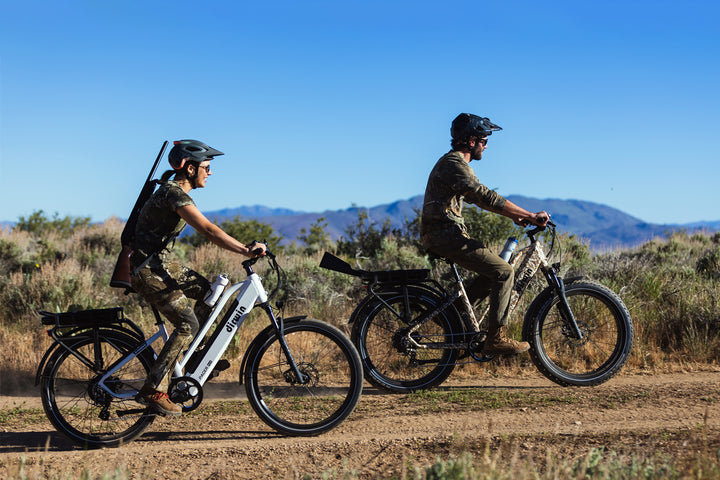 two people riding Dirwin Pioneer Plus Fat Tire Electric Bikes on rough terrain offroad in the desert