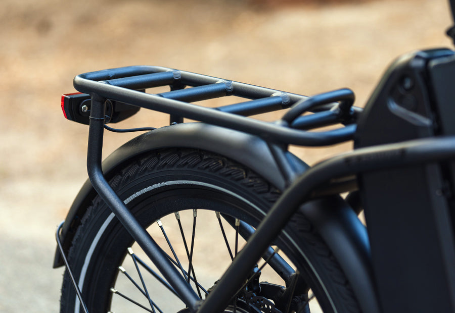 Close-up of an electric bike's rear wheel with cargo rack and brake light.